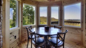 A wooden cabin with a round table and chairs, large windows offering a view of the outdoors. - ⭐️Prime Location with Stunning Views, Hot Tub, Game Room⭐️ (Gatlinburg)