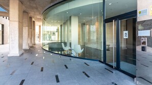 A modern interior with a curved glass wall, seating area, and a security keypad on the wall.