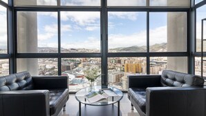 A modern room with two leather sofas facing a large window offering a city view.