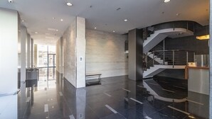 A spacious lobby with a polished floor, a central seating area, and a staircase leading to upper levels.