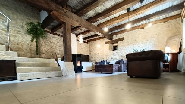 A spacious living area with a stone wall, a fireplace, and a sofa. - PALACIO CASA RURAL LOS LAMBREQUINES in Villacomparada de Rueda.  (Villacomparada de Rueda)