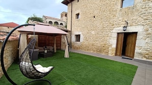 A stone building with a hanging chair and artificial grass in the courtyard. - PALACIO CASA RURAL LOS LAMBREQUINES in Villacomparada de Rueda.  (Villacomparada de Rueda)