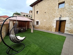 Un edificio de piedra con una hamaca y césped artificial en el patio.