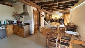 A rustic kitchen with wooden cabinets, a microwave, and a stove. There is a dining area with a wooden table and chairs. - PALACIO CASA RURAL LOS LAMBREQUINES in Villacomparada de Rueda.  (Villacomparada de Rueda)