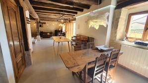 A rustic dining area with a wooden table and chairs, a stone wall, and a window with a view. - PALACIO CASA RURAL LOS LAMBREQUINES in Villacomparada de Rueda.  (Villacomparada de Rueda)