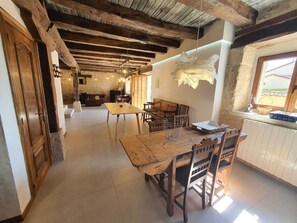 Un comedor rústico con una mesa y sillas de madera, una pared de piedra y una ventana con vistas.