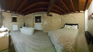 A bedroom with a large bed, a built-in bathtub, a bedside table, and a wardrobe. - PALACIO CASA RURAL LOS LAMBREQUINES in Villacomparada de Rueda.  (Villacomparada de Rueda)
