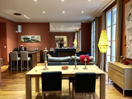 Una sala de estar moderna con una mesa de comedor, sillas, un sofá y una zona de cocina al fondo.