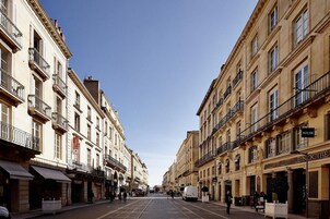Calle flanqueada por edificios con balcones y escaparates.