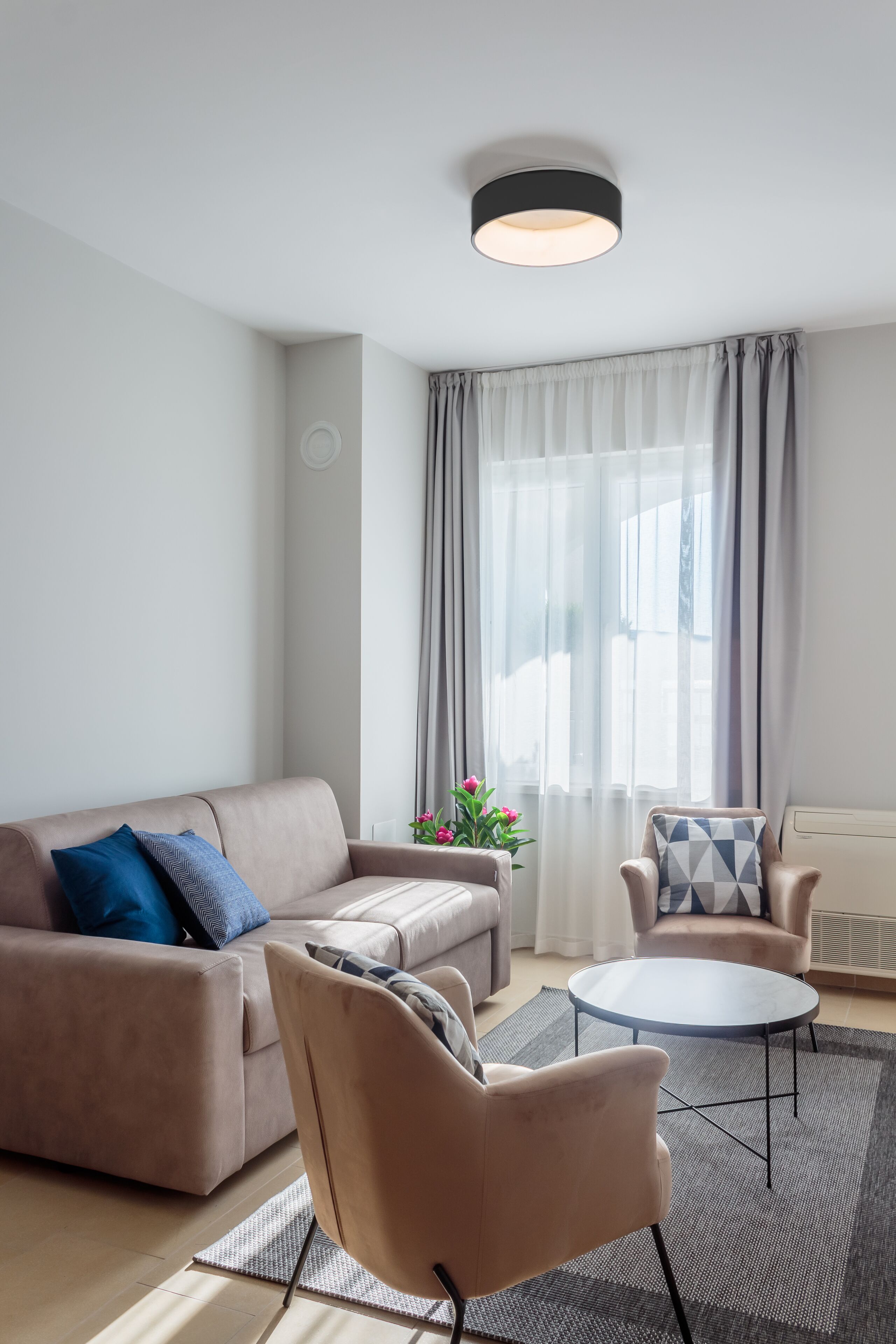 A modern living room with a sofa, armchair, and round coffee table.
