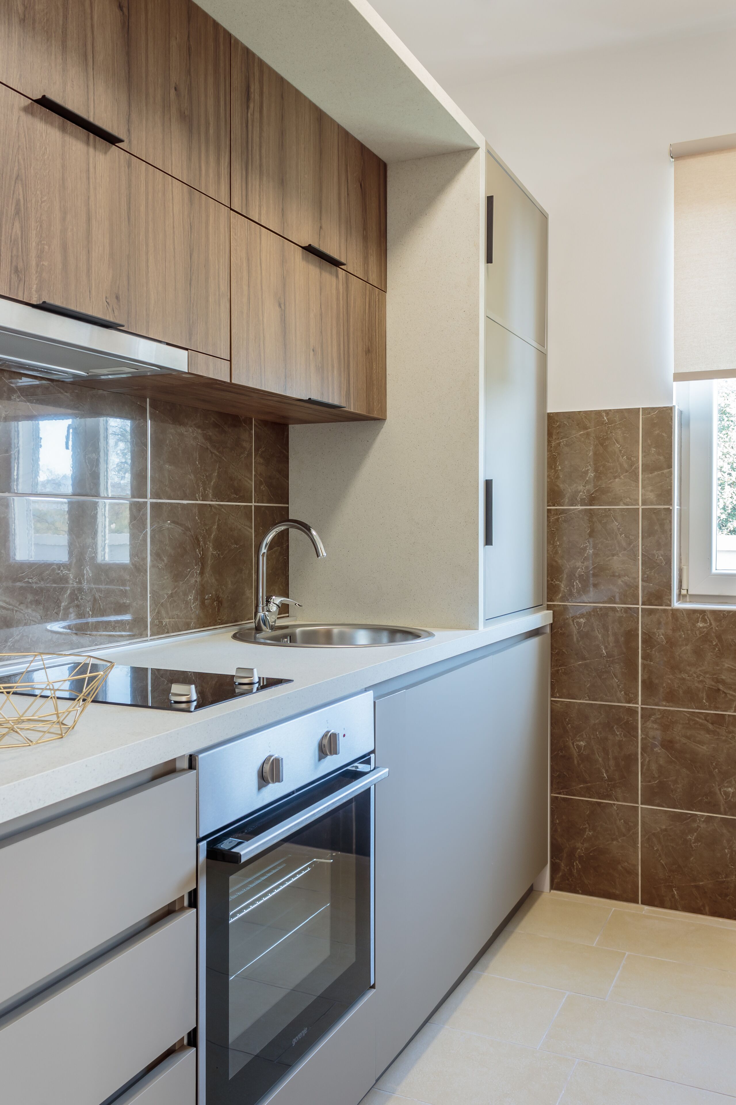 A modern kitchen with wooden cabinets, a stainless steel sink, and a built-in oven.