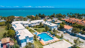 A resort with multiple buildings, a swimming pool, and a view of the ocean. - Porto Luar Apart Hotel (Santa Cruz Cabralia)