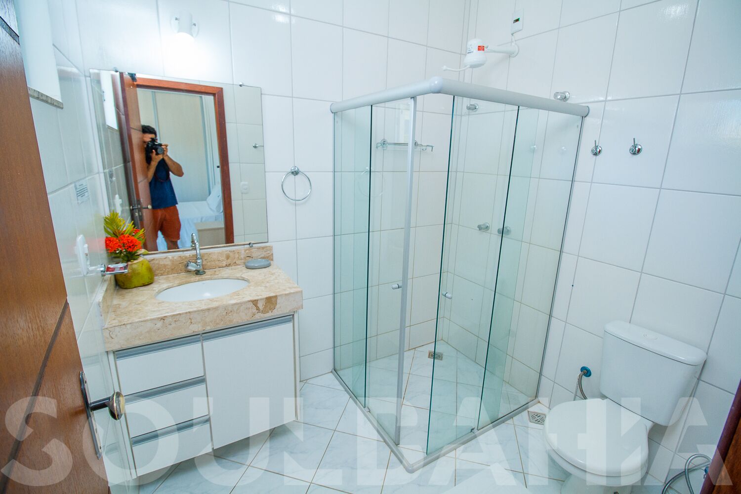 A modern bathroom with a glass-enclosed shower, a sink with a marble countertop, and a toilet.