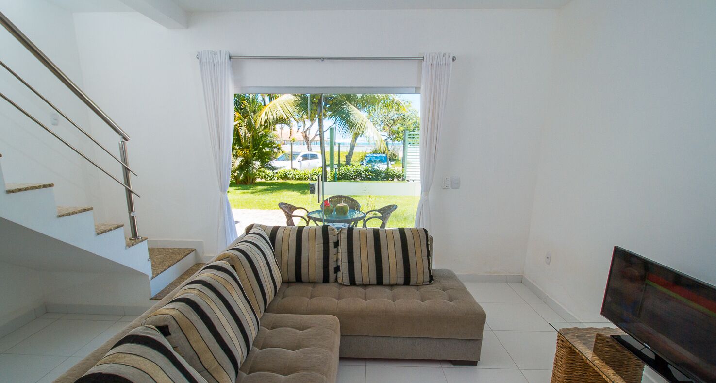 Ein Wohnzimmer mit Sofa, Fernseher und Blick auf Garten und Straße.