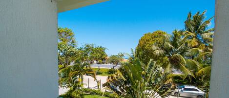 A balcony with a clear view of a parking area, palm trees, and a building in the background.