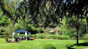 A garden with a gazebo, a pond, and neatly trimmed bushes.