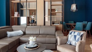 A modern living room with a sectional sofa, a round coffee table, and a dining area with chairs. - Apartments (Tivat)