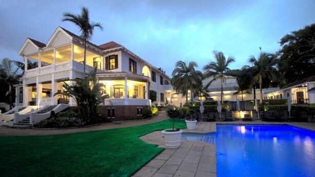 A large, two-story house with a swimming pool, surrounded by palm trees and a well-maintained lawn. - Audacia Manor Boutique Hotel (Berea)