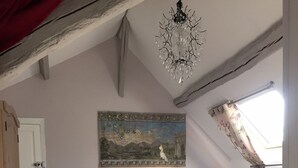 A bedroom with a bed, a bench, a nightstand, a painting, a chandelier, and a window with curtains. - Les Colonnes de Chanteloup (Amboise)