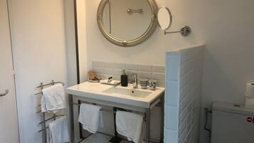 Ein Badezimmer mit weißem Waschbecken, einem Spiegel, einem Handtuchhalter und einer Toilette.