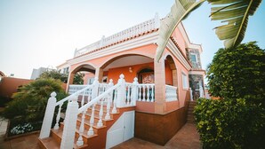 Un immeuble à plusieurs étages, doté d’une façade rose, de balcons blancs et d’un escalier menant à l’entrée.