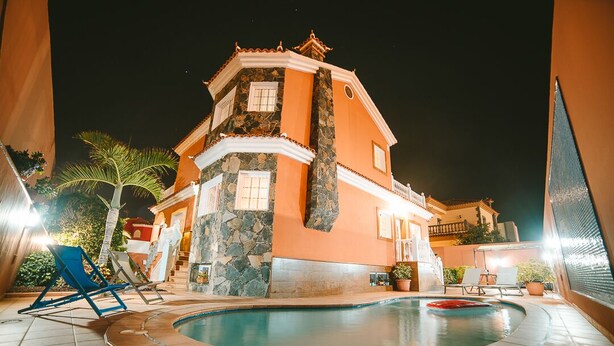 Un bâtiment à deux étages doté d’une piscine, d’une façade en pierre et d’un balcon avec une balustrade.