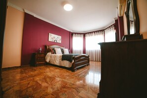 A bedroom with a large bed, a dresser, and a mirror.