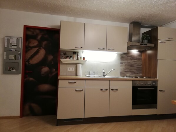 A modern kitchen with beige cabinets, a stainless steel sink, and a built-in oven.