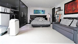 A modern bedroom with a bed, a sofa, a TV, and a large abstract painting. - Mio Lofts (Medellín)