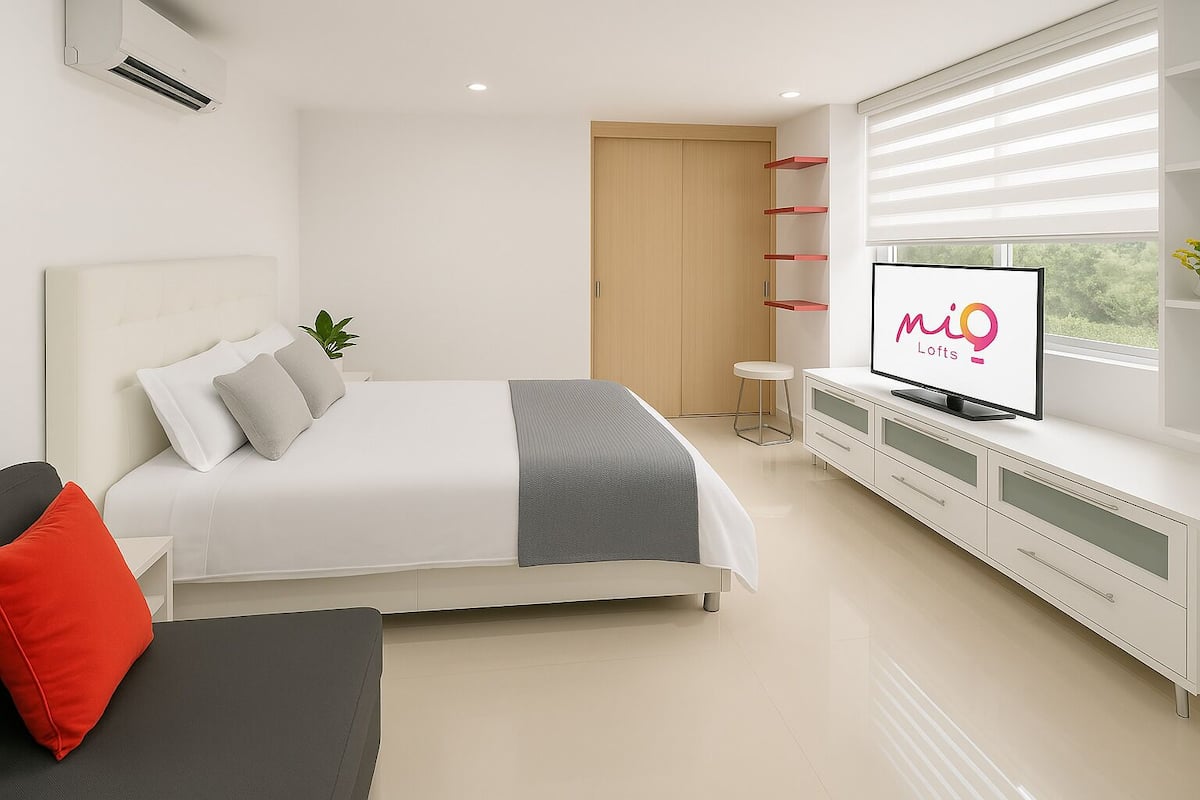 A modern bedroom with a bed, a TV, a wardrobe, and a window with blinds.