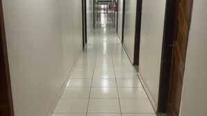A long, narrow hallway with white walls and tiled floors, leading to multiple doors at the end. - Hotel Novo Gama (Novo Gama)