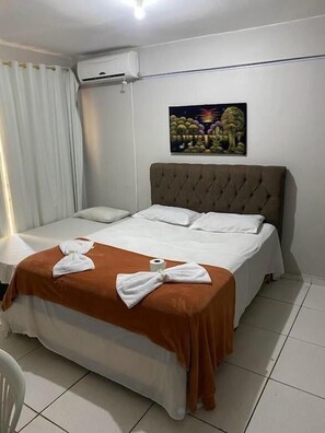 A hotel room with a bed, white curtains, an air conditioning unit, and a painting on the wall. - Hotel Novo Gama (Novo Gama)