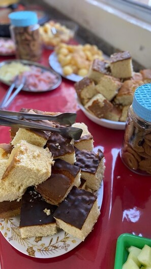 Una mesa con distintos alimentos, incluyendo un plato de pasteles con cobertura de chocolate y un tarro de nueces.