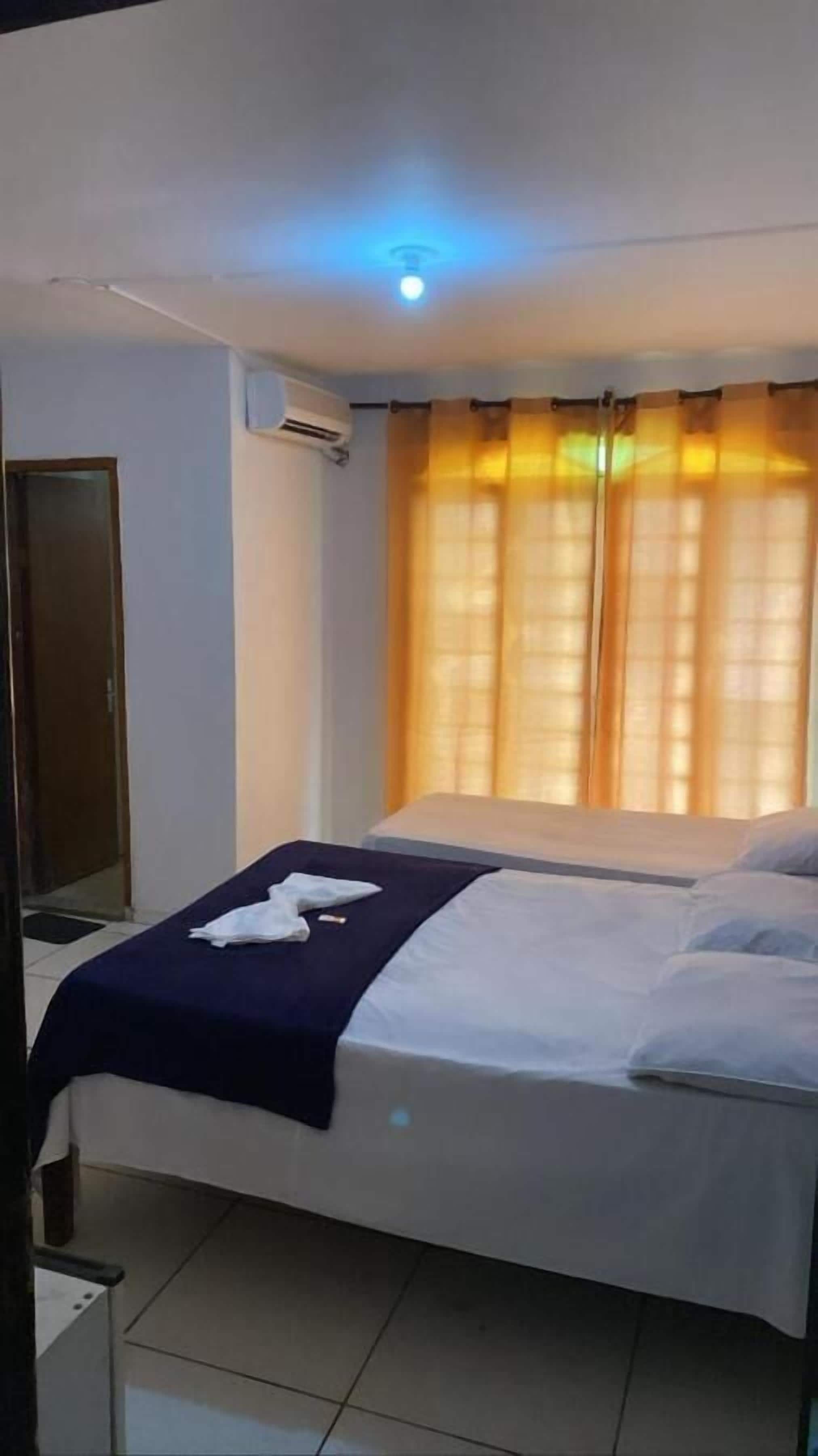 Une chambre d’hôtel avec un lit, une table de chevet et une fenêtre avec des rideaux.