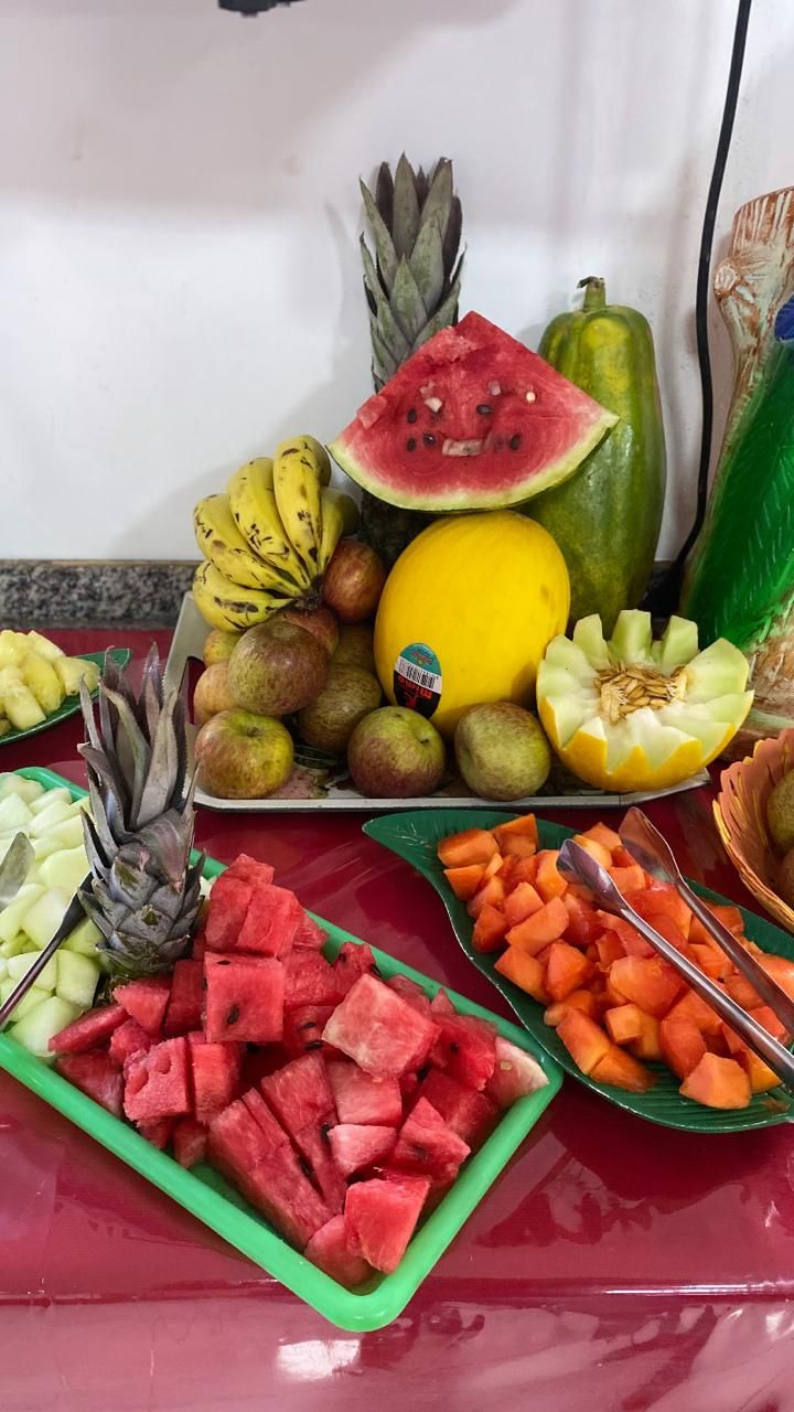 A table with various fruits and vegetables, including watermelon, pineapple, and apples.