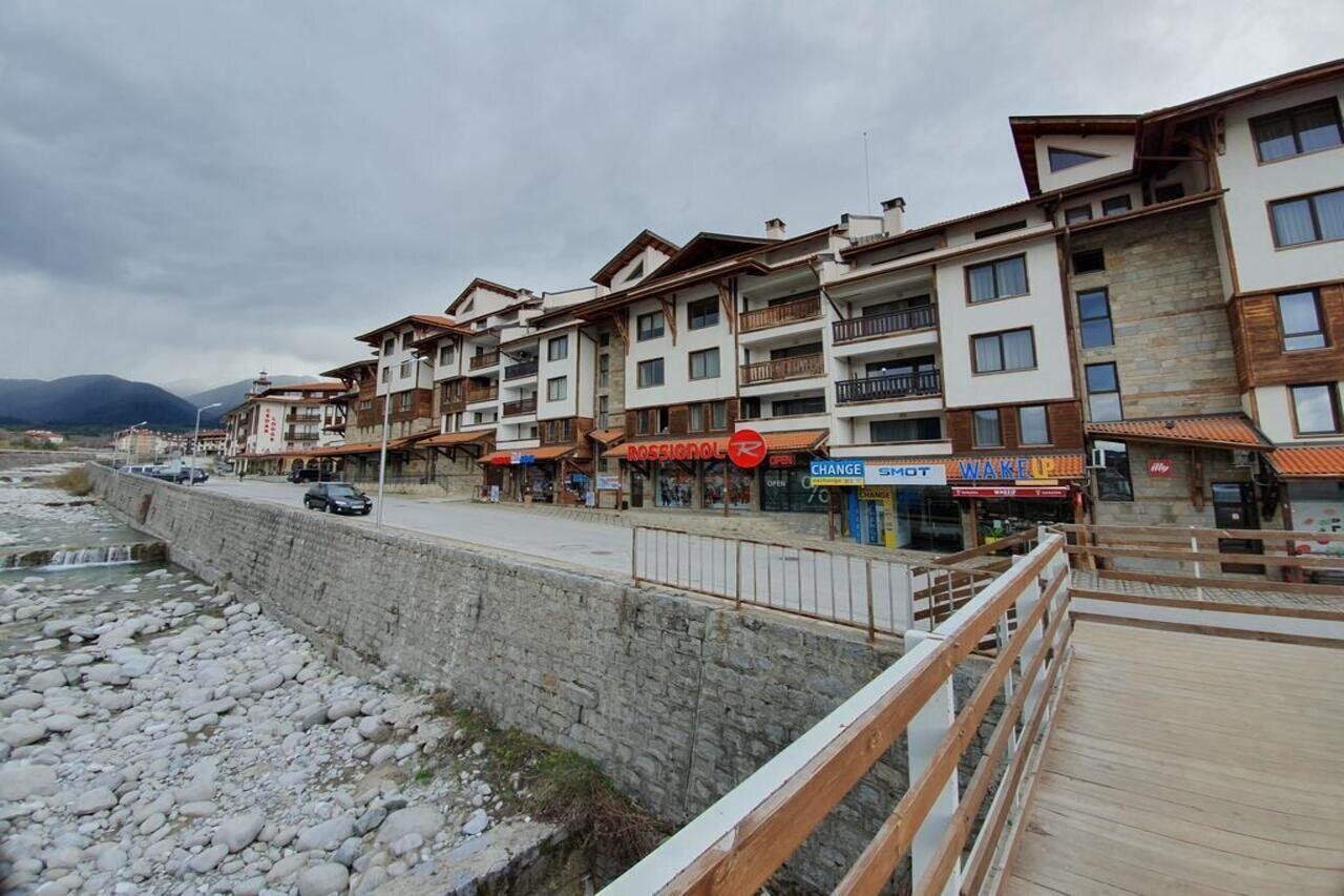 Una hilera de edificios de varios pisos con balcones, un muro de piedra de contención y un paseo marítimo de madera.