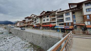 Una hilera de edificios de varios pisos con balcones, un muro de piedra de contención y un paseo marítimo de madera.