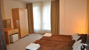 A hotel room with a bed, a wardrobe, a desk, and a mirror. - Bansko Royal Towers - Apartments (Bansko)