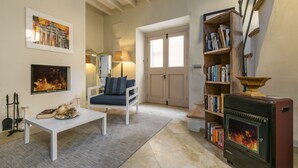 A cozy living room with a fireplace, a sofa, a coffee table, and a bookshelf.