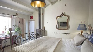 A bedroom with a bed, a dresser, a mirror, and a window with curtains.