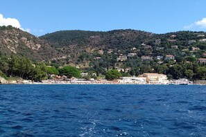A coastal town with buildings on a hillside, a beach, and boats in the water. - NEW: Air-conditioned apartment with wifi (Le Lavandou)