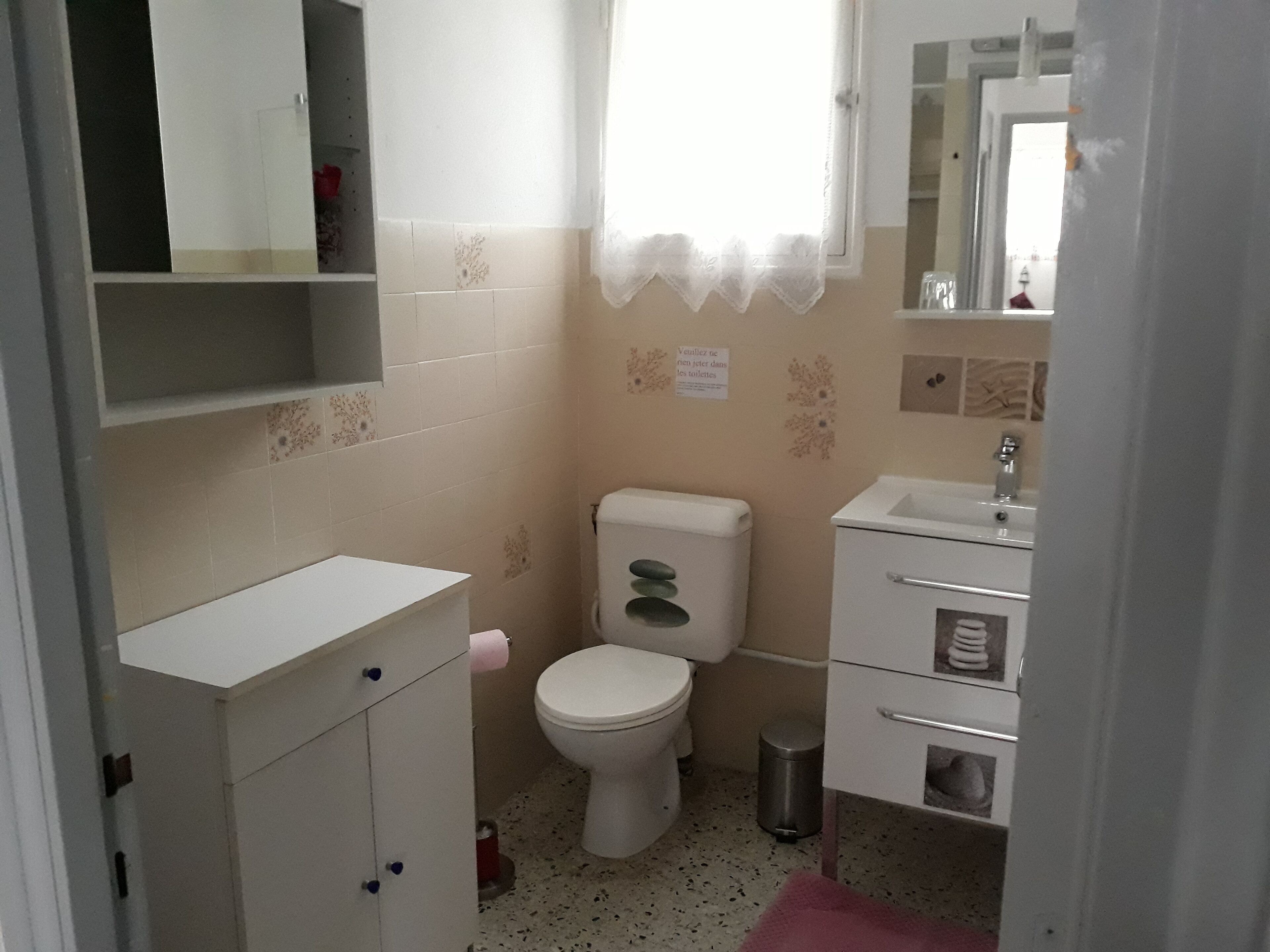 Un baño pequeño y funcional con inodoro, lavamanos y armarios para guardar.