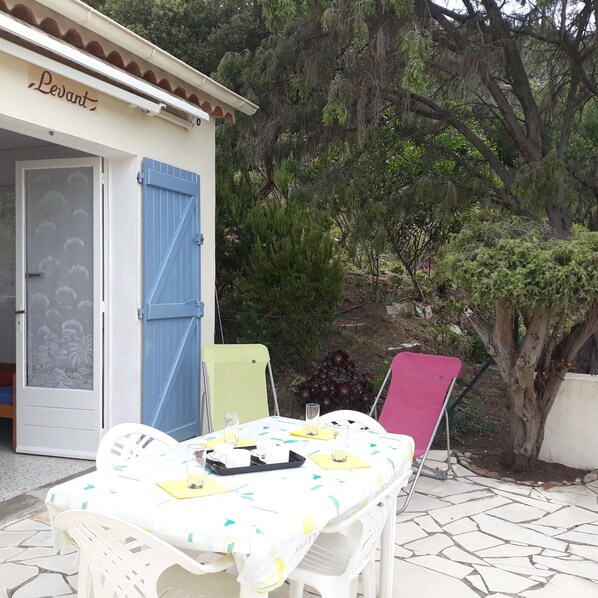 An outdoor dining area with a table set for two, a blue door, and a sign reading "Levant". - NEW: Air-conditioned apartment with wifi (Le Lavandou)