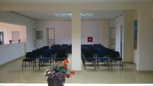 A room with rows of chairs, a reception desk, and a potted plant with flowers. - Jardin Hotel Belgrade (Belgrade)