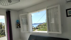 Ett sovrum med en säng, ett litet bord och ett fönster med gardiner.