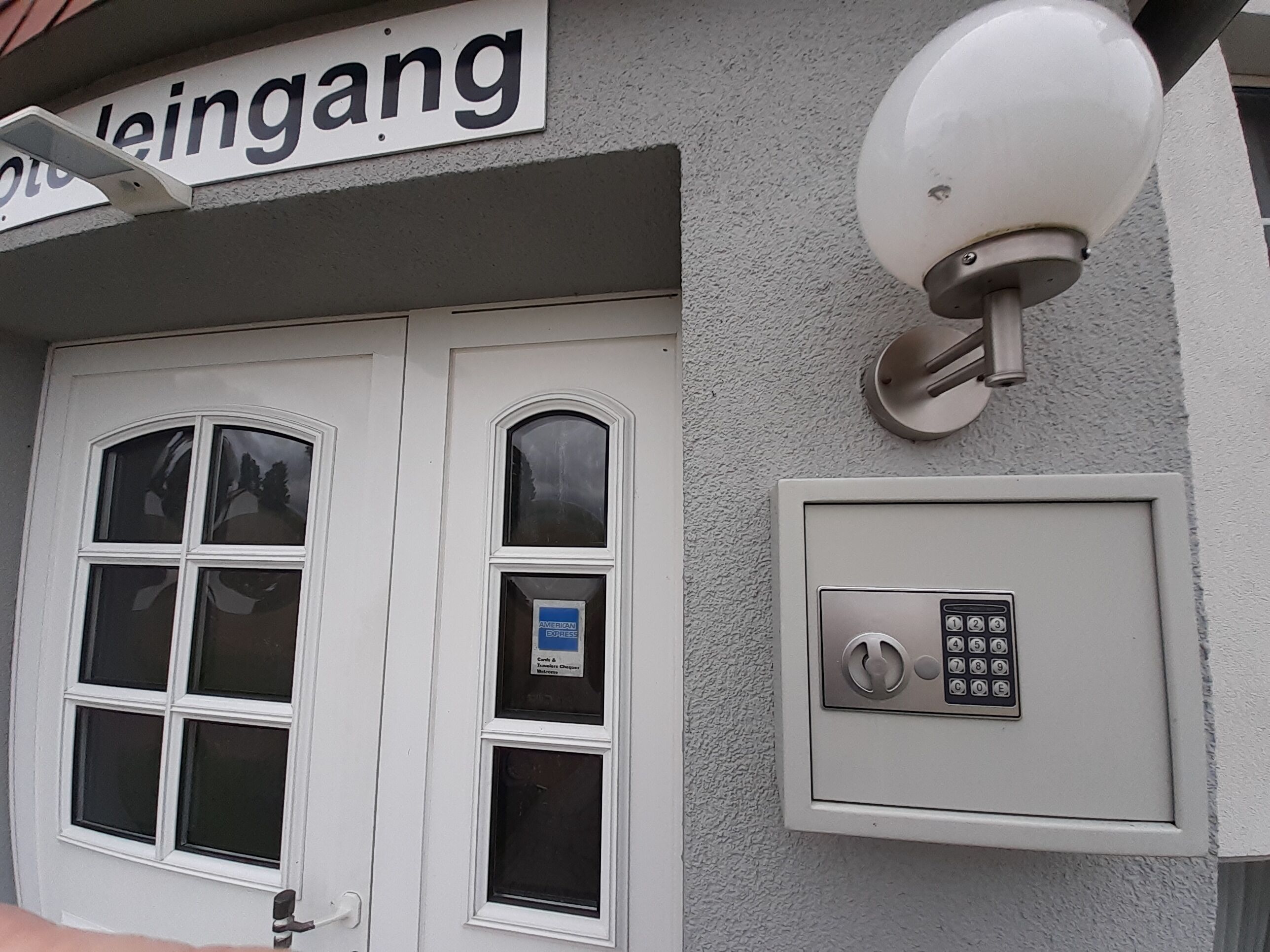A building entrance with a double door, a security camera, and a keypad lock.