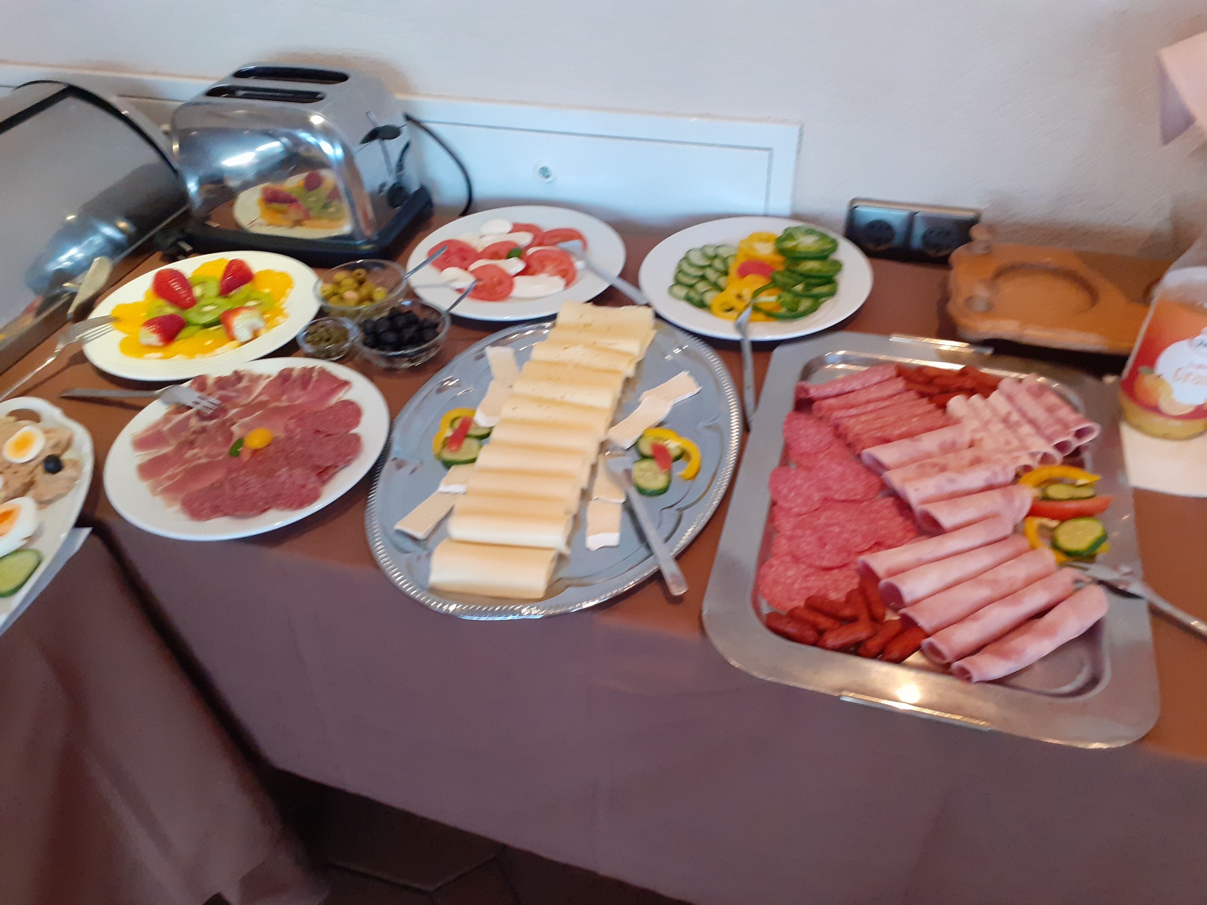 Noutopöytä, jossa on tarjolla monenlaista ruokaa, kuten lihaa, juustoja ja vihanneksia.
