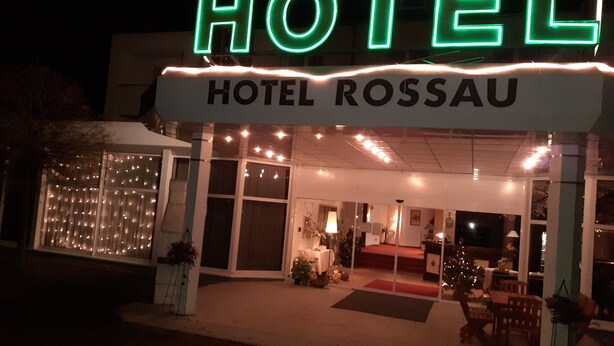 A hotel with a neon sign reading "HOTEL ROSSAU" and a well-lit entrance. - Edit Pension Rossau (Rossau)