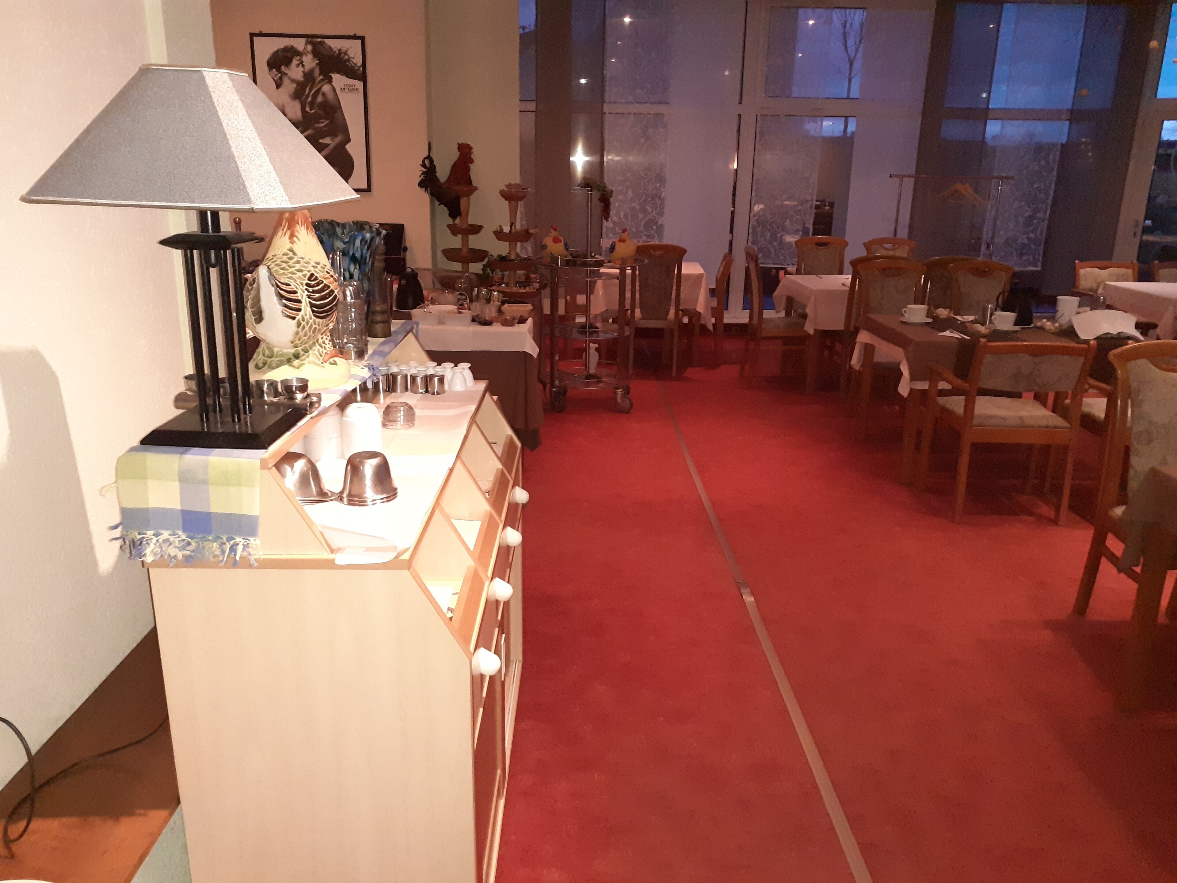 A dining area with tables and chairs, a lamp, and a display of kitchenware.