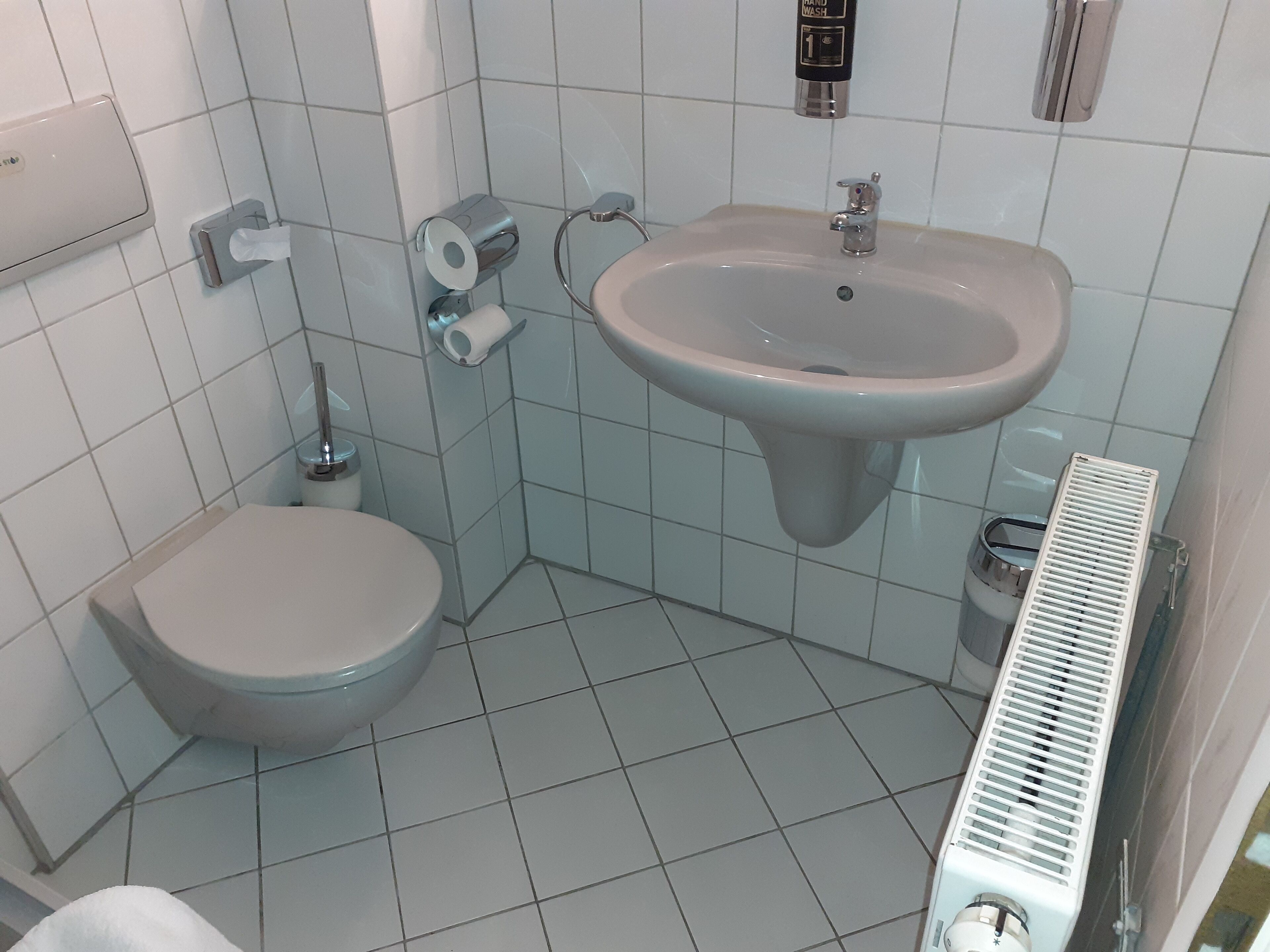 A bathroom with a toilet, sink, and hand dryer.